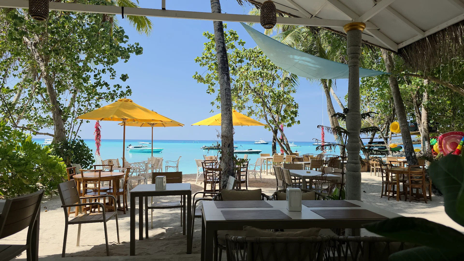 Open-air beachfront dining under the palms at Kinān Beach Club, Fulidhoo